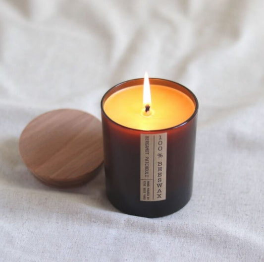 Beeswax candle in a brown glass jar with a wooden lid and kraft paper brown label