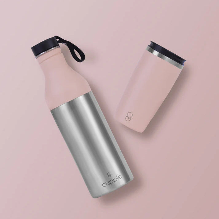 An insulated metal bottle with a pink top and silver bottom with a pink coffee cup beside it, on a pink background.