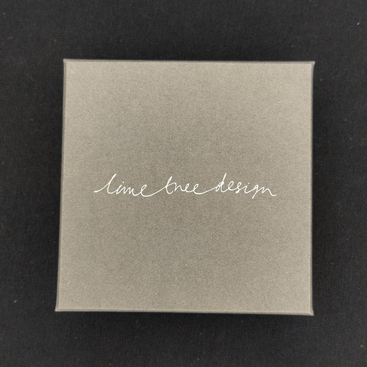 A square matt grey box with handwritten style font saying Lime Tree Design