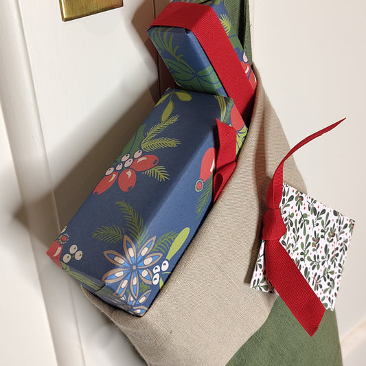 Close up view of the top of a filled Christmas stocking showing presents wrapped in blue with red ribbon.