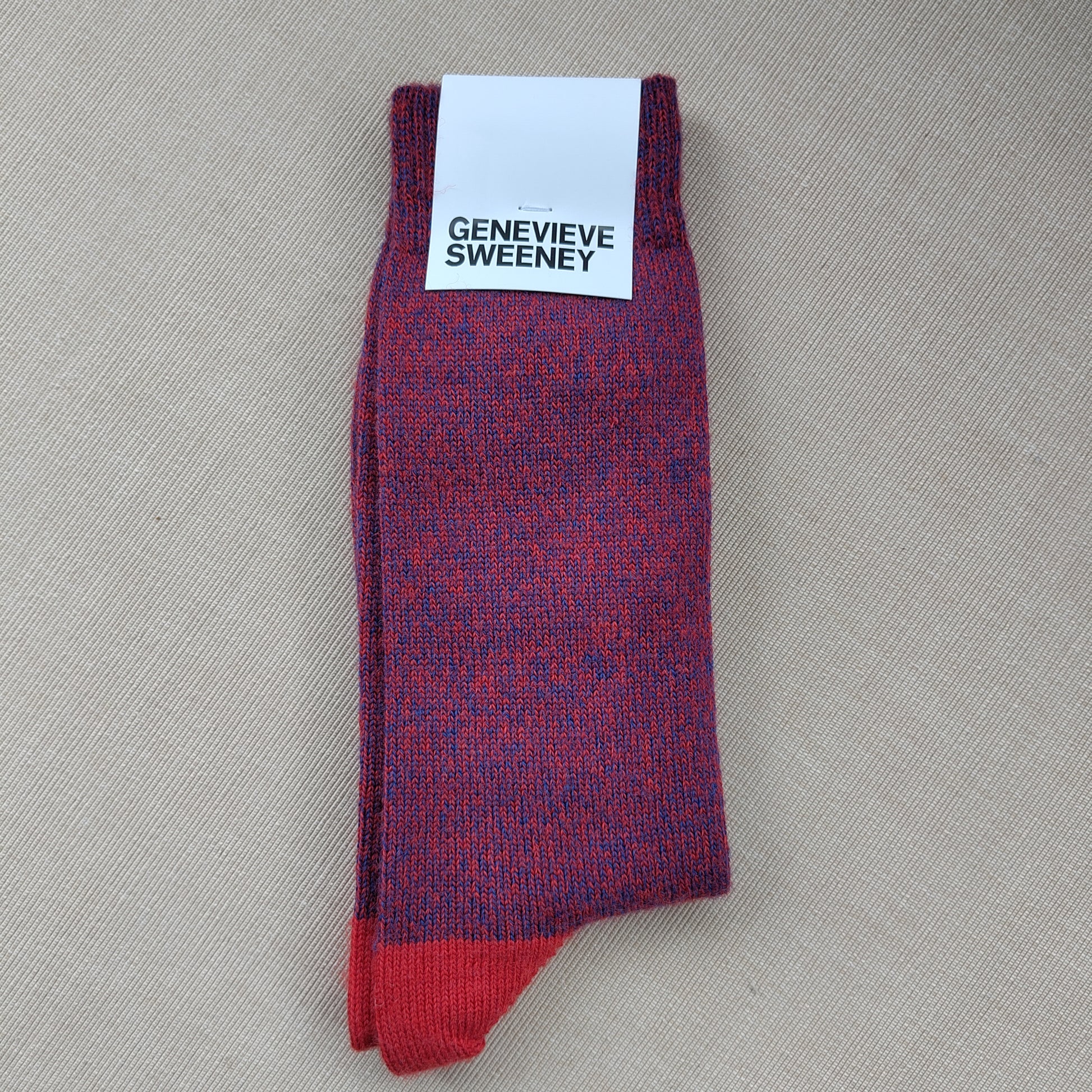 A folded pair of wool socks with a label saying Genevieve Sweeney
