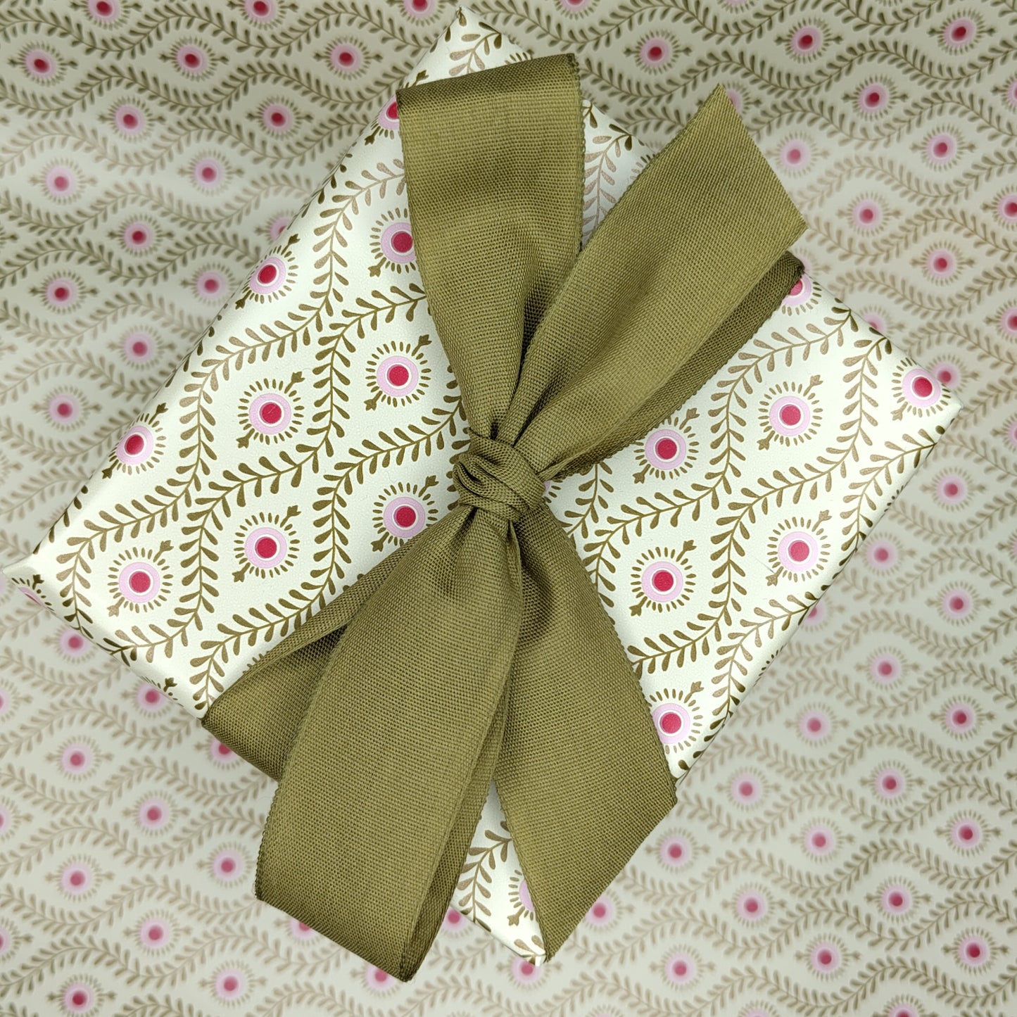 Present wrapped in gold patterned paper with a gold ribbon