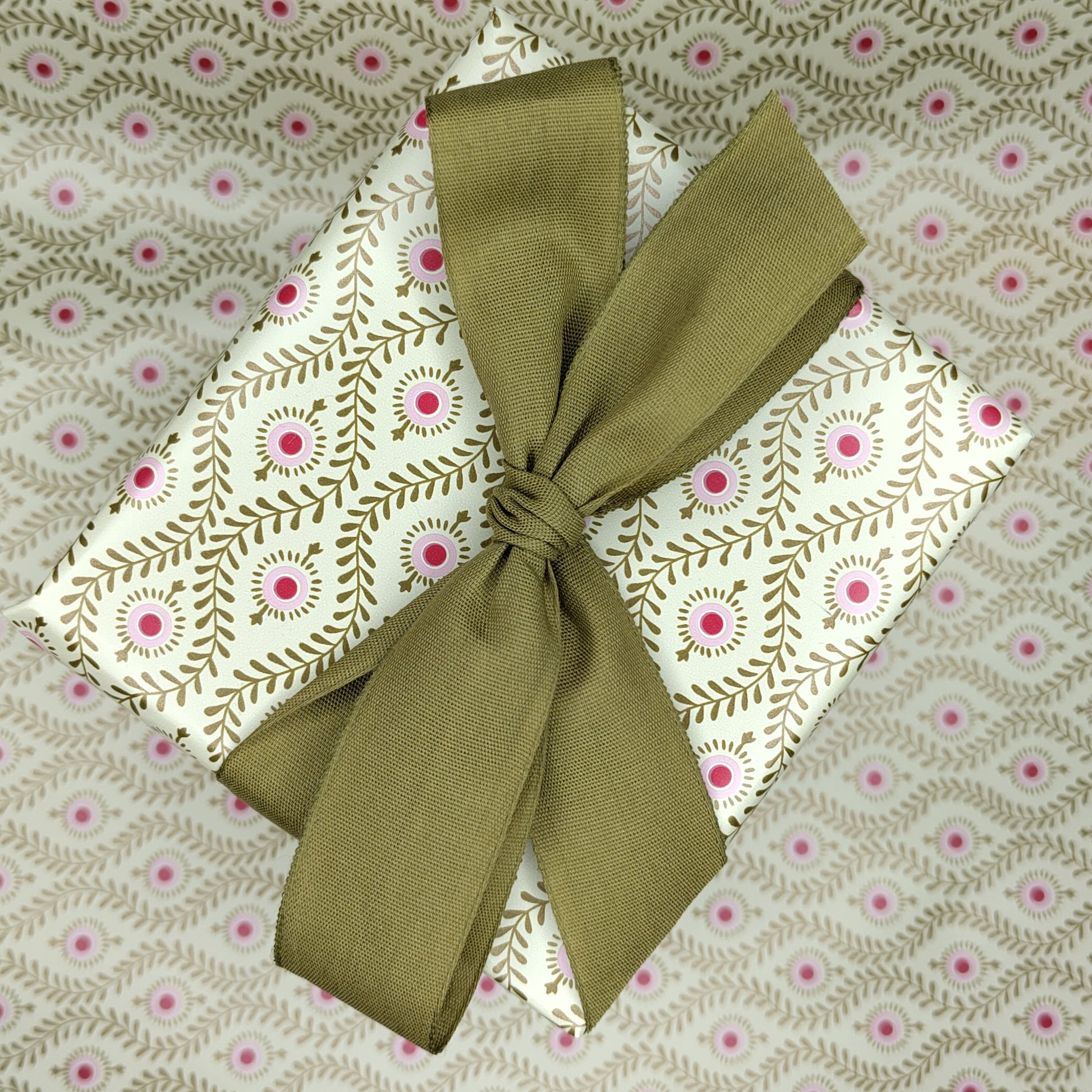 Present wrapped in gold patterned paper with a gold ribbon