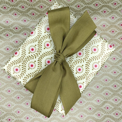 Present wrapped in gold patterned paper with a gold ribbon