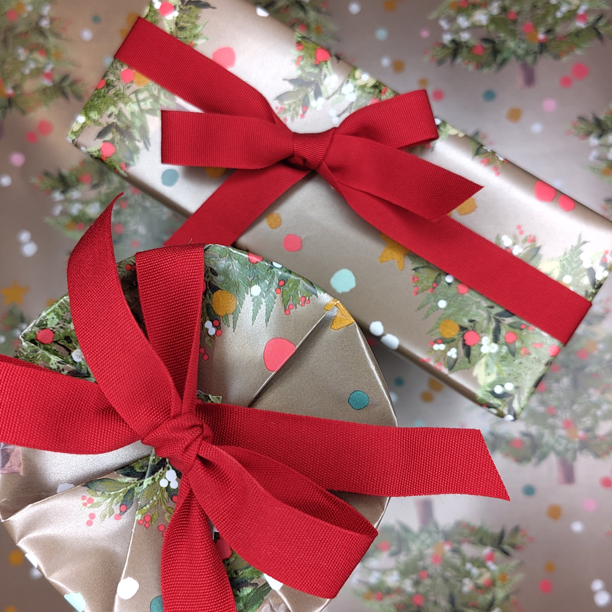 Two wrapped presents in gold paper with red ribbons on a festive background