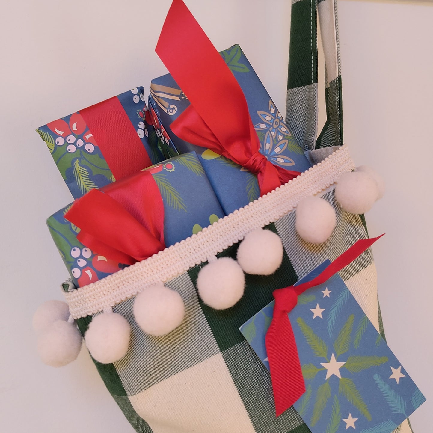 Wrapped presents in decorative blue, red and green gift wrap with red ribbons poking out of a Christmas stocking