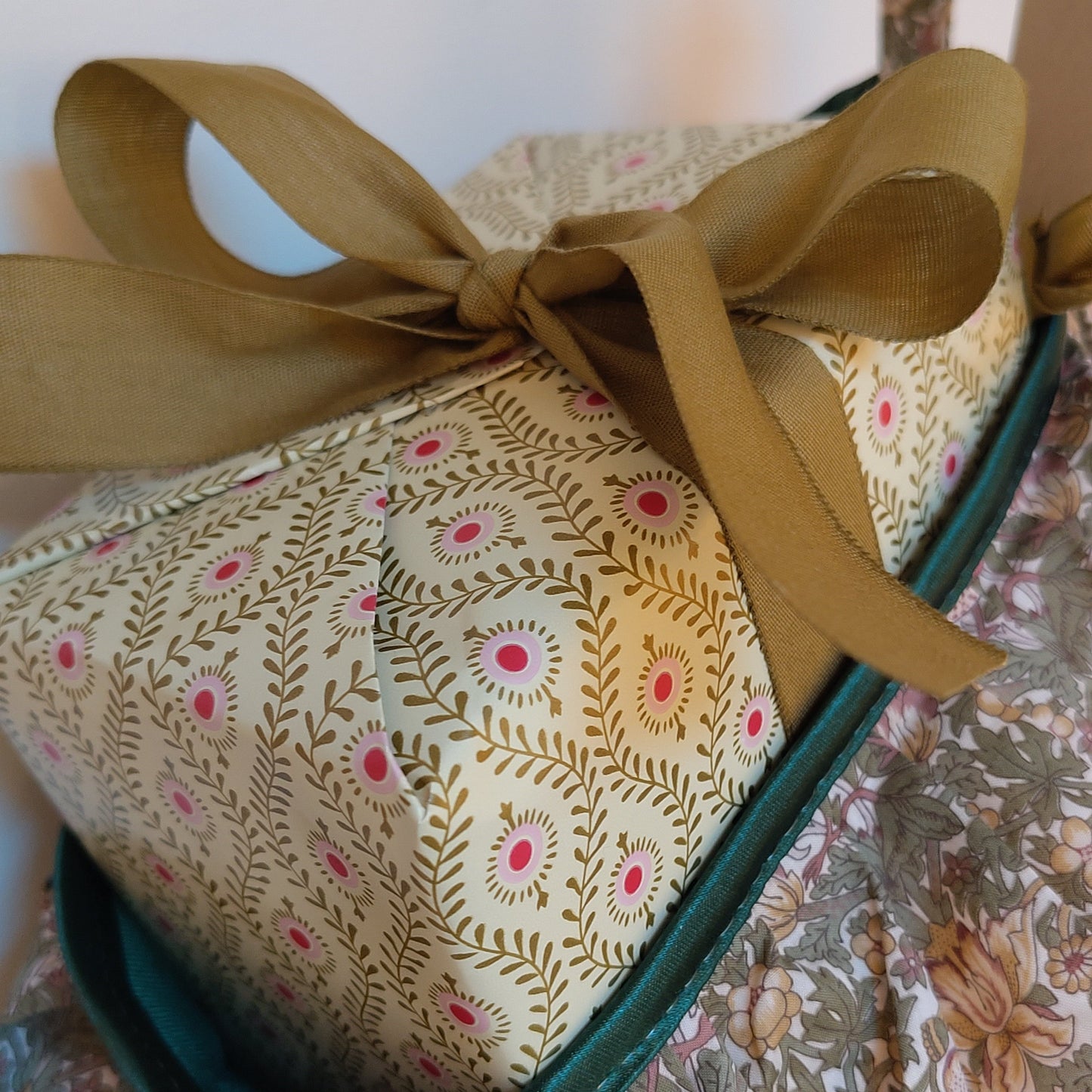 Close up of the top of a stocking with a present sticking out, wrapped in gold and pink paper with a gold ribbon