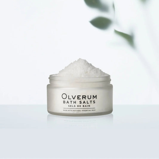 Jar of Olverum bath salts with a blurred green leafy background