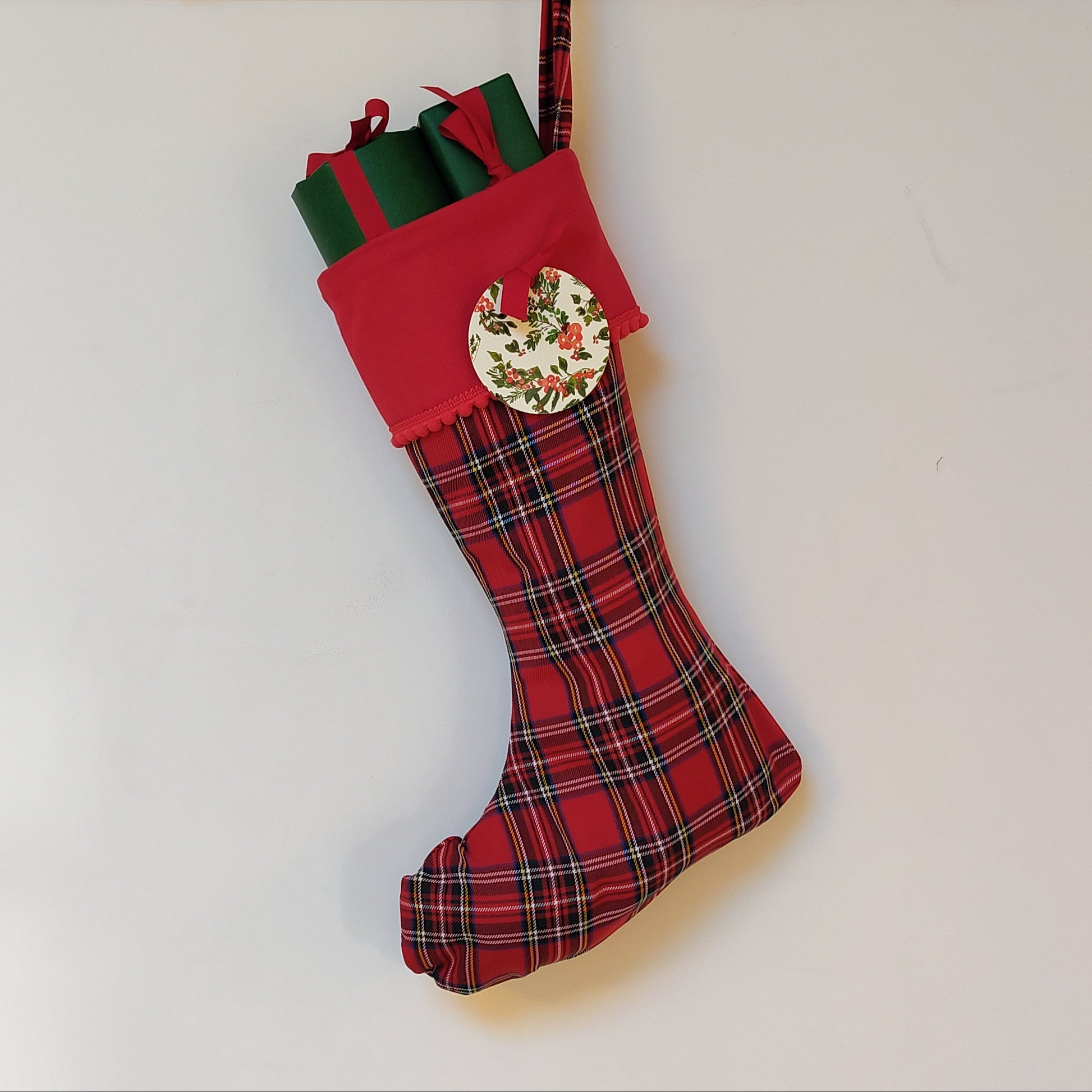 Red plaid Christmas stocking filled with wrapped presents on a white background