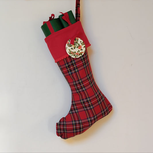 Red plaid Christmas stocking filled with wrapped presents on a white background