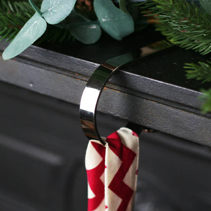 Silver hook on a dark grey mantelpiece holding a red and white Christmas Stocking hook.