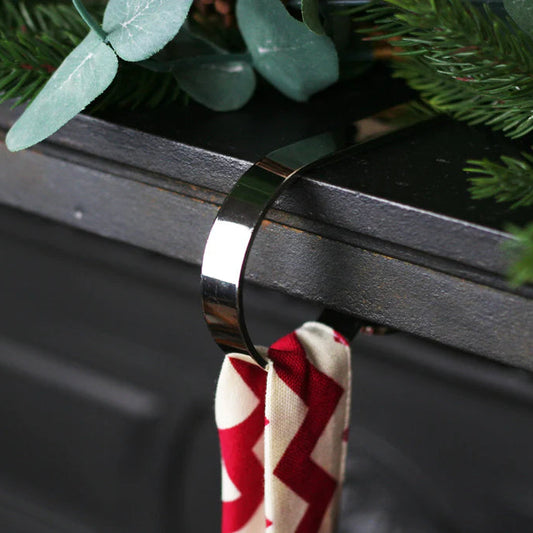 Silver hook on a dark grey mantelpiece holding a red and white Christmas Stocking hook.