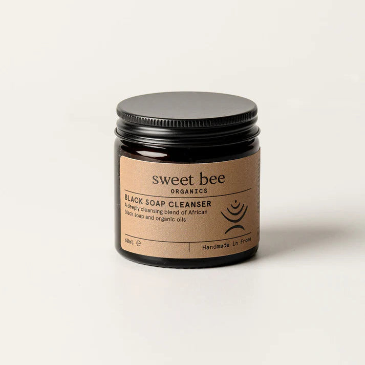 Brown glass jar with metal lid of African Black Soap Cleanser on a white background