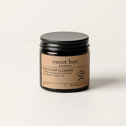 Brown glass jar with metal lid of African Black Soap Cleanser on a white background