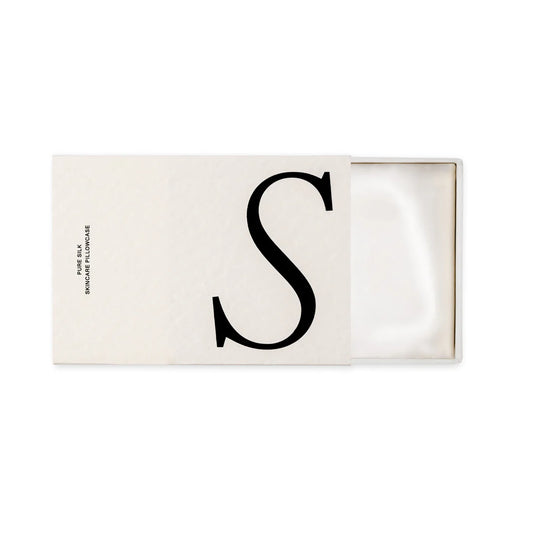 Rectangular white box with letter 'S' on a white background that is open to show a white folded silk pillowcase inside