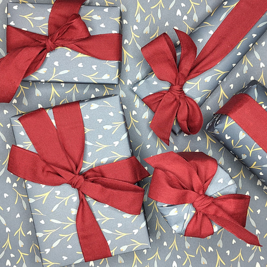 Gift boxes wrapped in gray paper with red ribbons on a matching patterned background